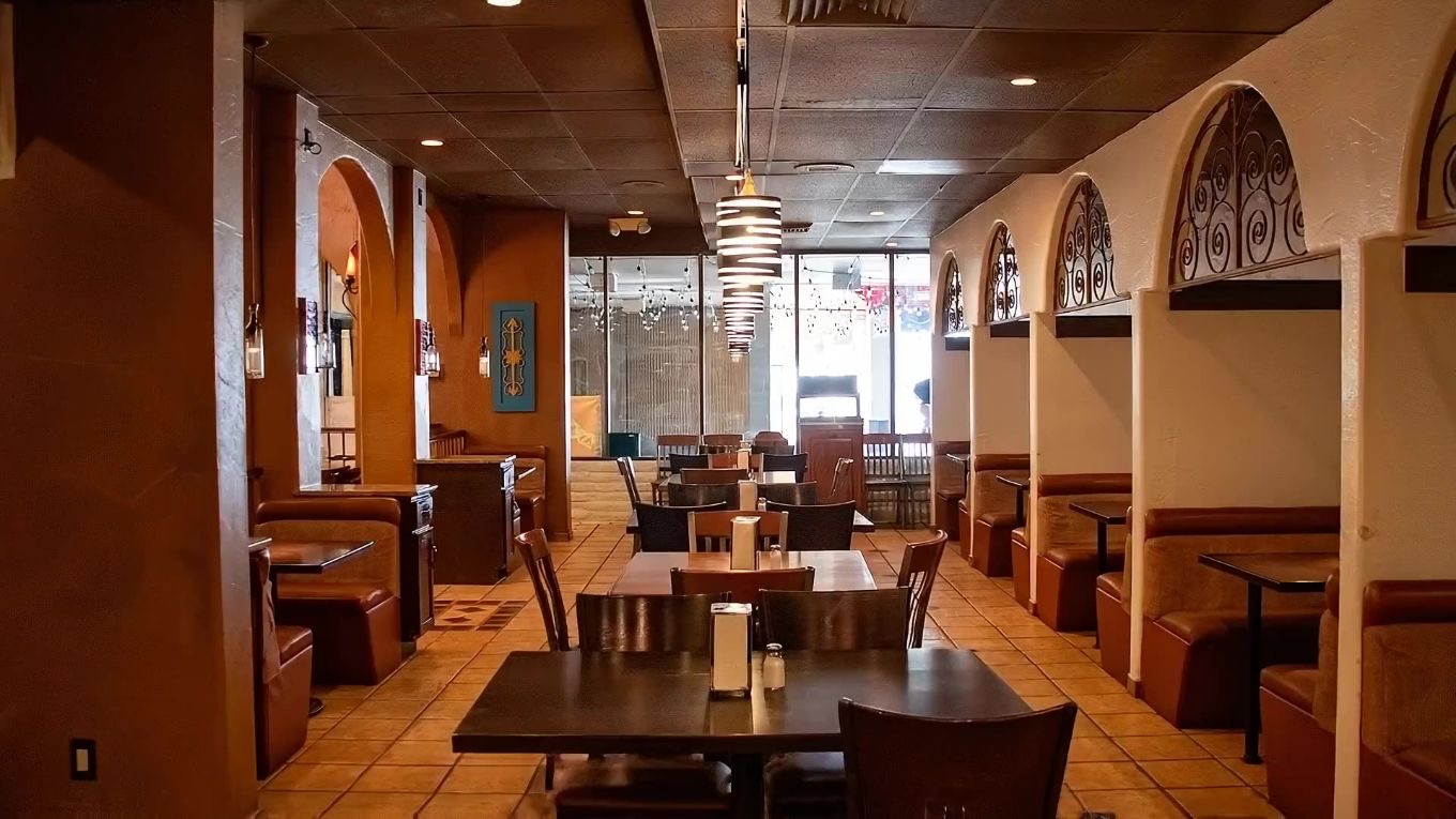 A booth at Tacos Ay Ay Ay framed by two adobe archways, looking through to the stairs and the order counter.
